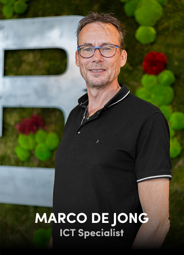 Portrait of Marco de Jong, ICT Specialist, in a black shirt with a green wall background.