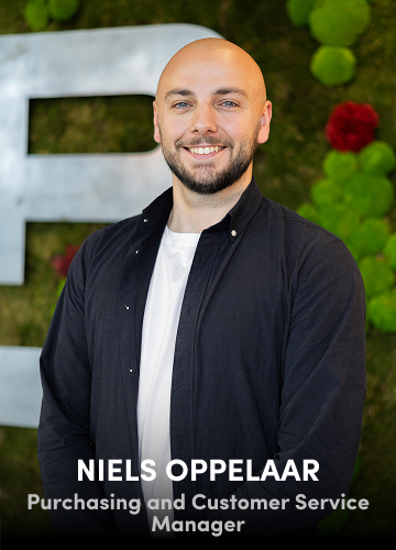 Portrait of Niels Oppelaar, Purchasing and Customer Service Manager, smiling in front of a green wall backdrop.