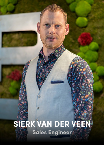 Portrait of Sierk van der Veen, Sales Engineer, wearing a patterned shirt and light vest against a green backdrop.