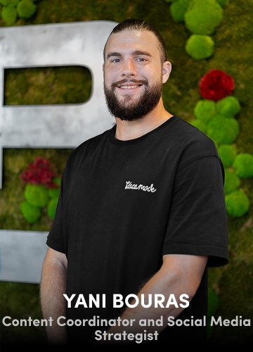 Portrait of Yani Bouras, Content Coordinator, in a black shirt with a green decorative wall in the background.