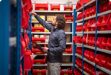 Employee in warehouse between red bins picking parts